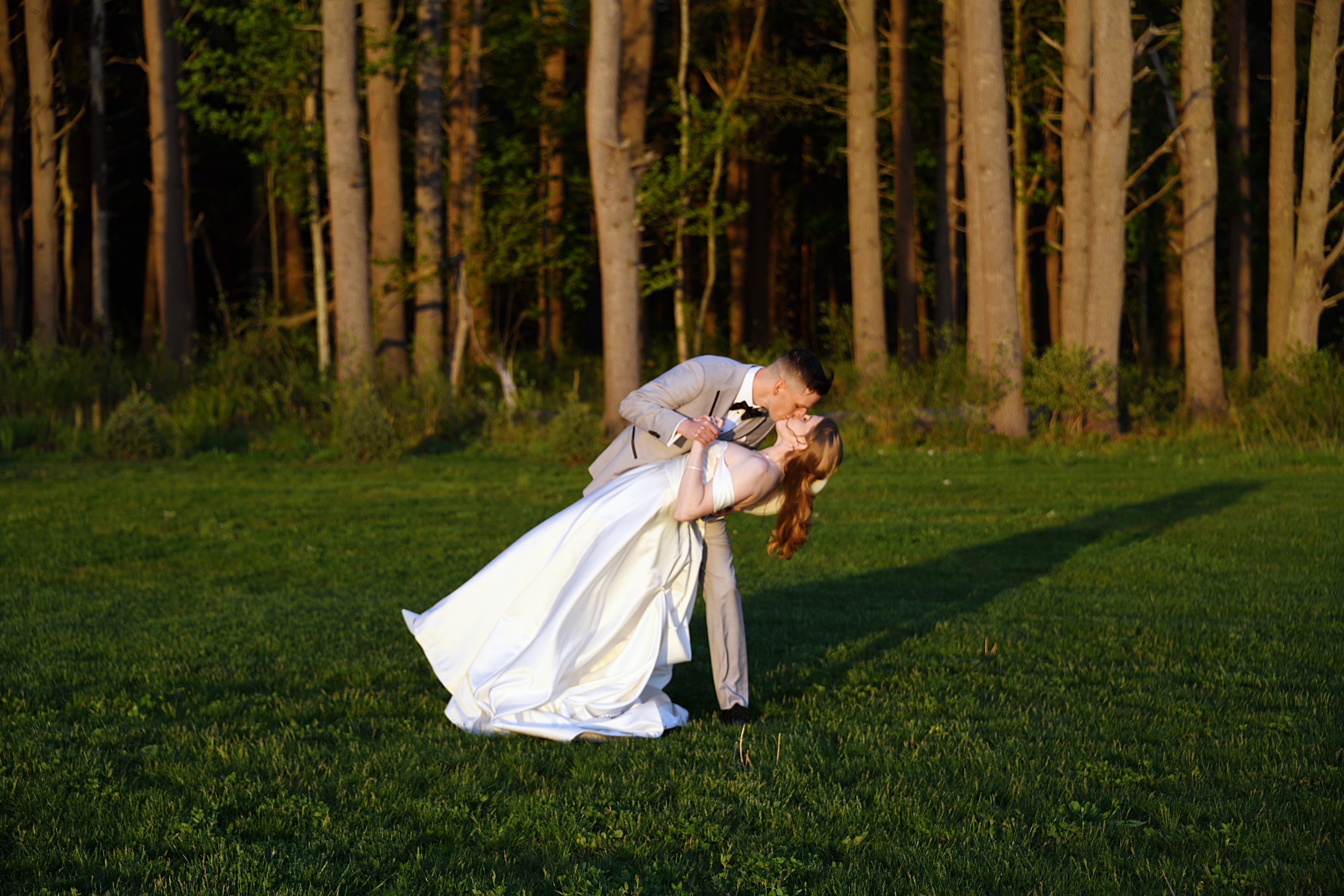 Groom dipping bride in a forest meadow