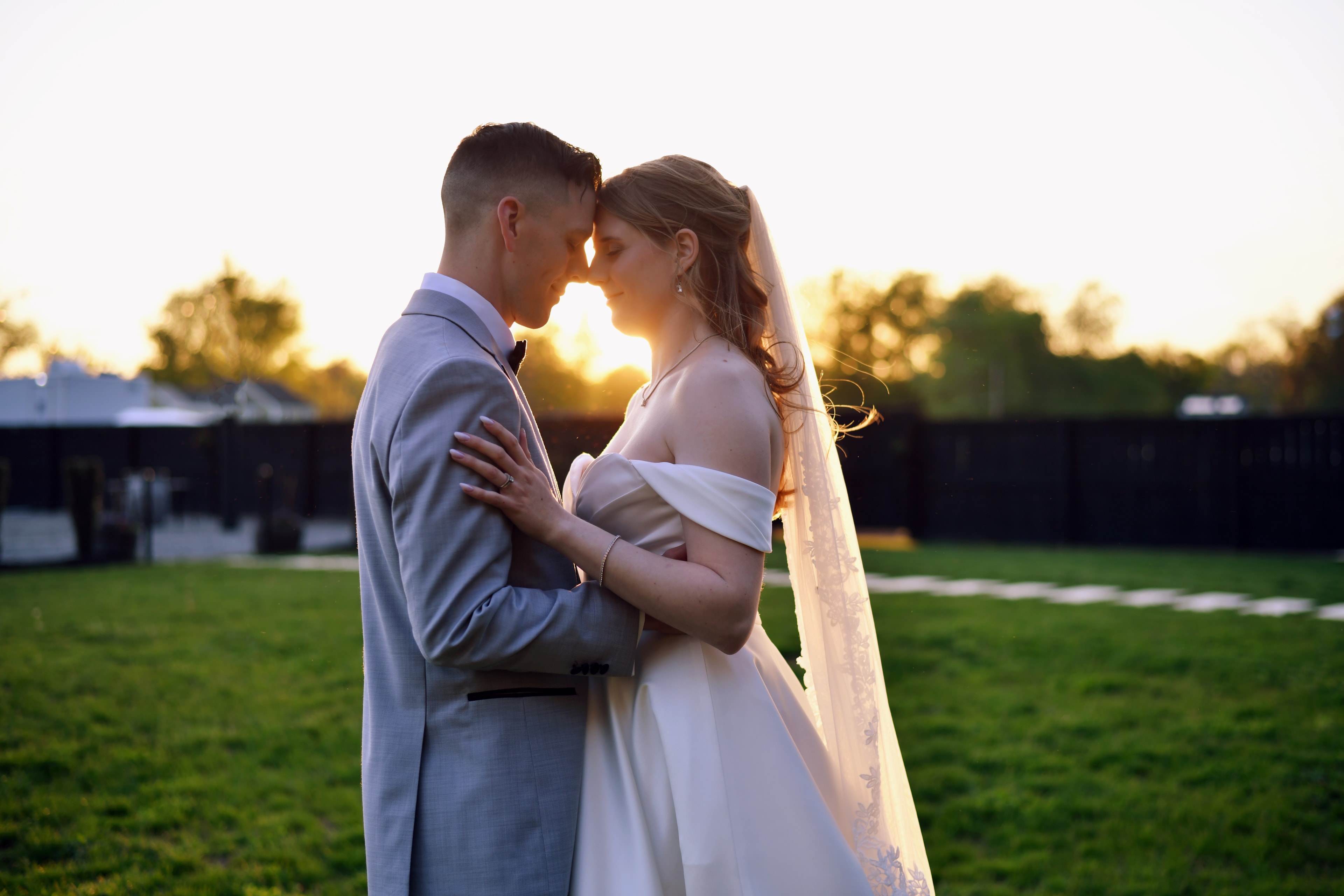 Bride and groom kissing at sunset in a field