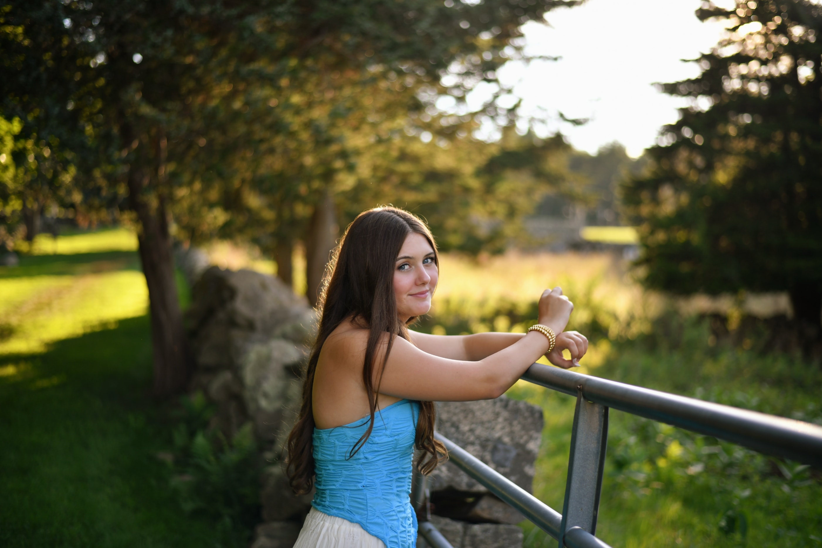 Senior portrait of young woman leaning on railing in lush garden