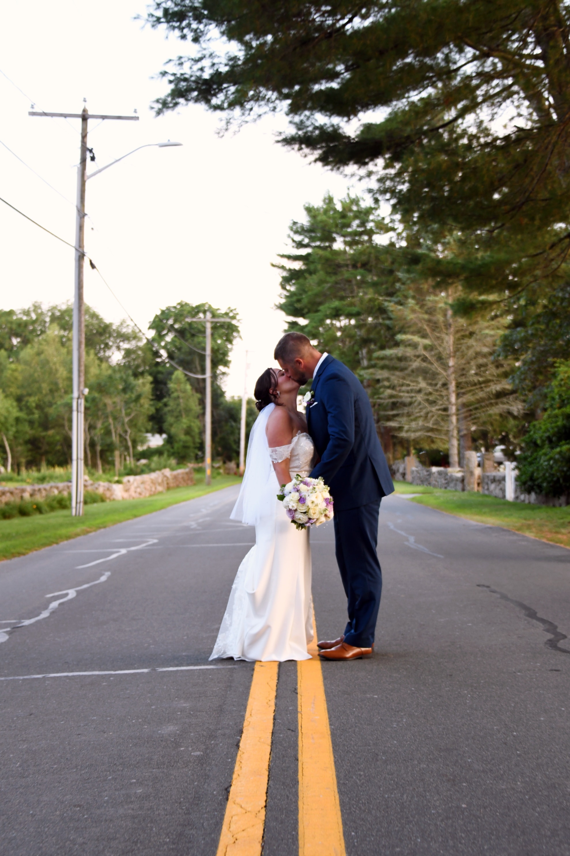 Bride and groom kissing in the middle of a road