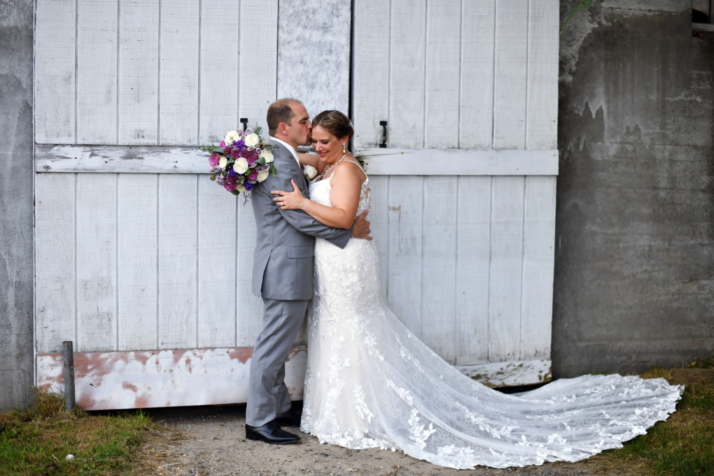 Bride and groom embracing against a weathered barn door