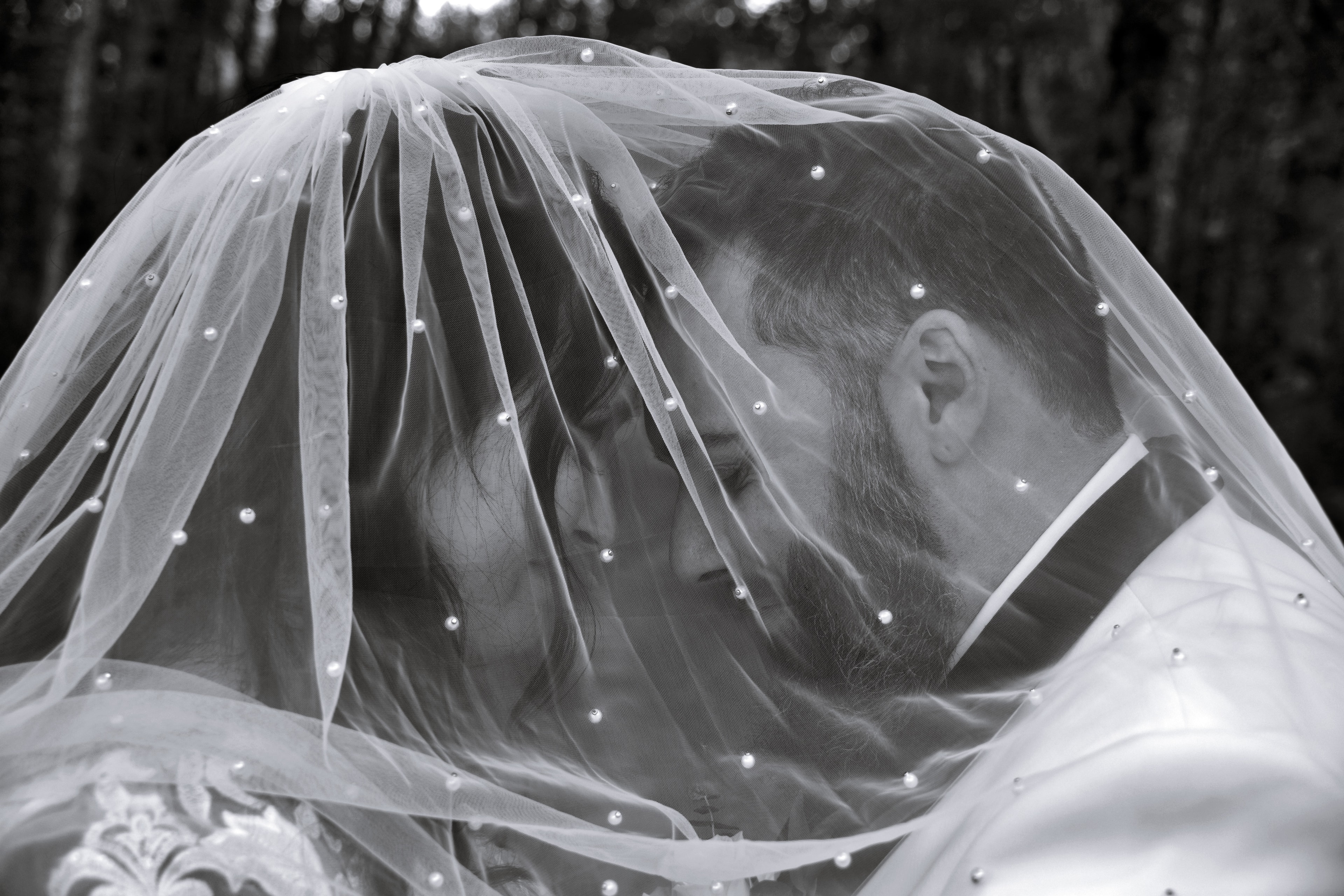Bride and groom under pearl veil in black and white
