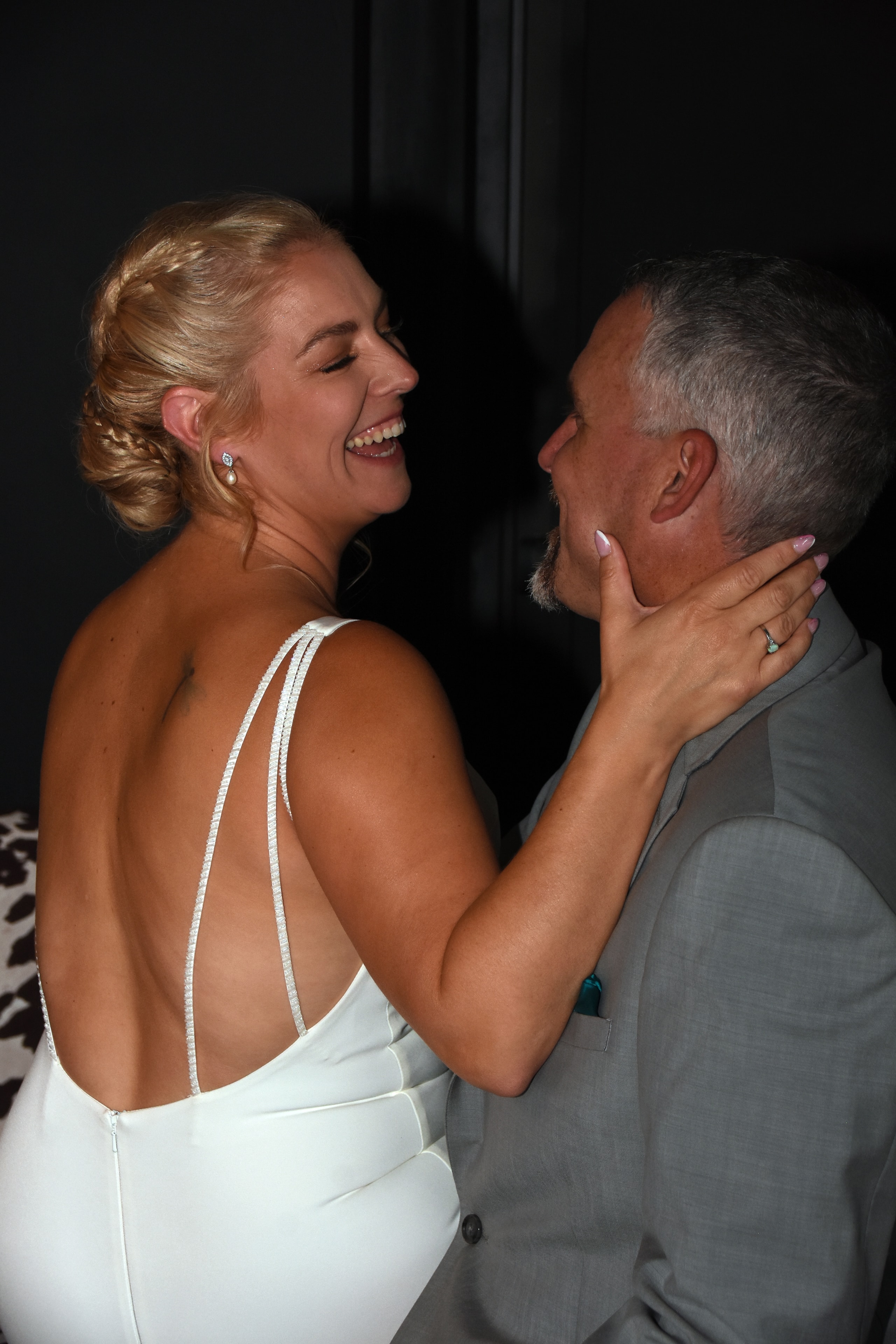 Bride laughing with groom in dark reception venue