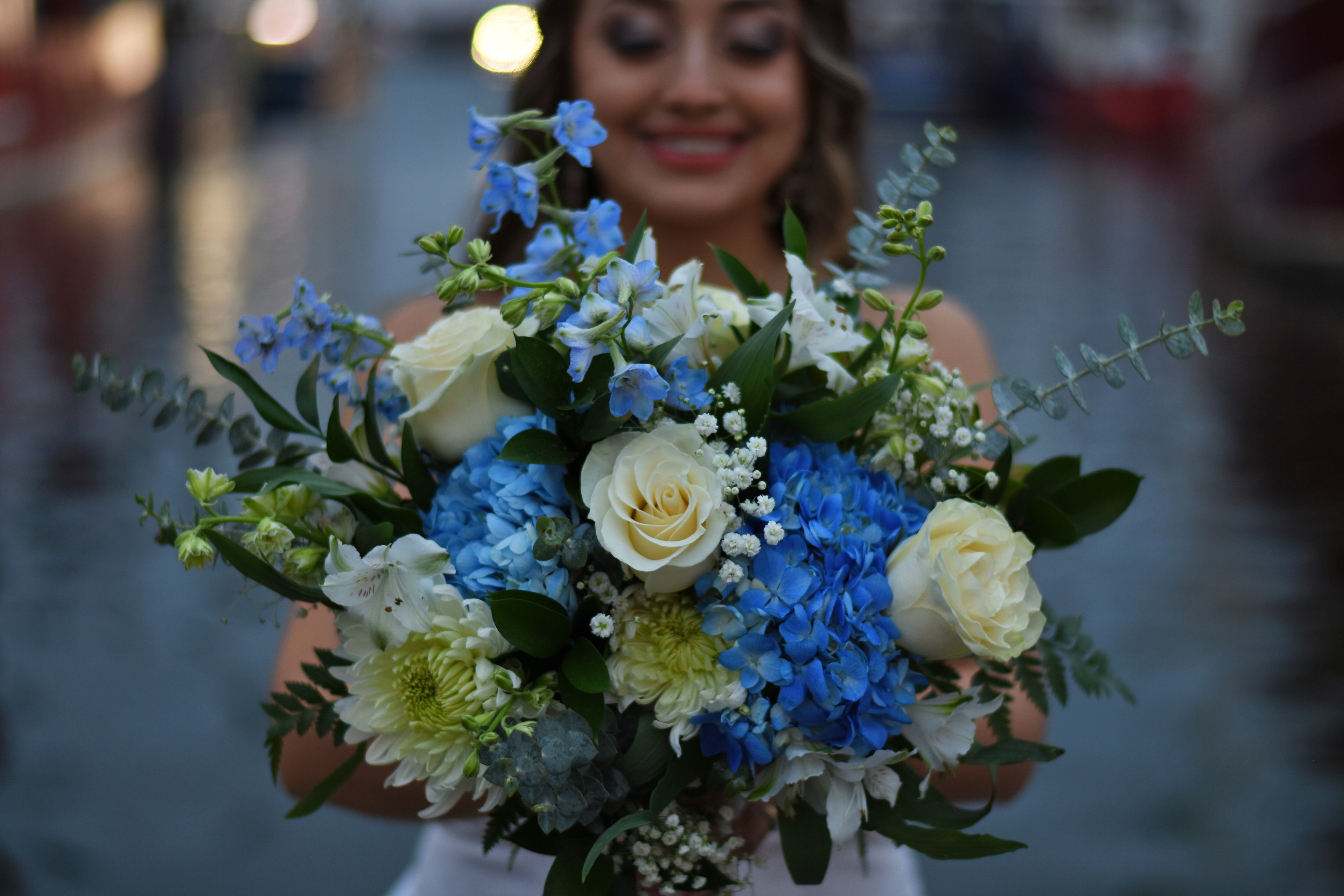 Bride holding blue and white hydrangea bouquet at dusk