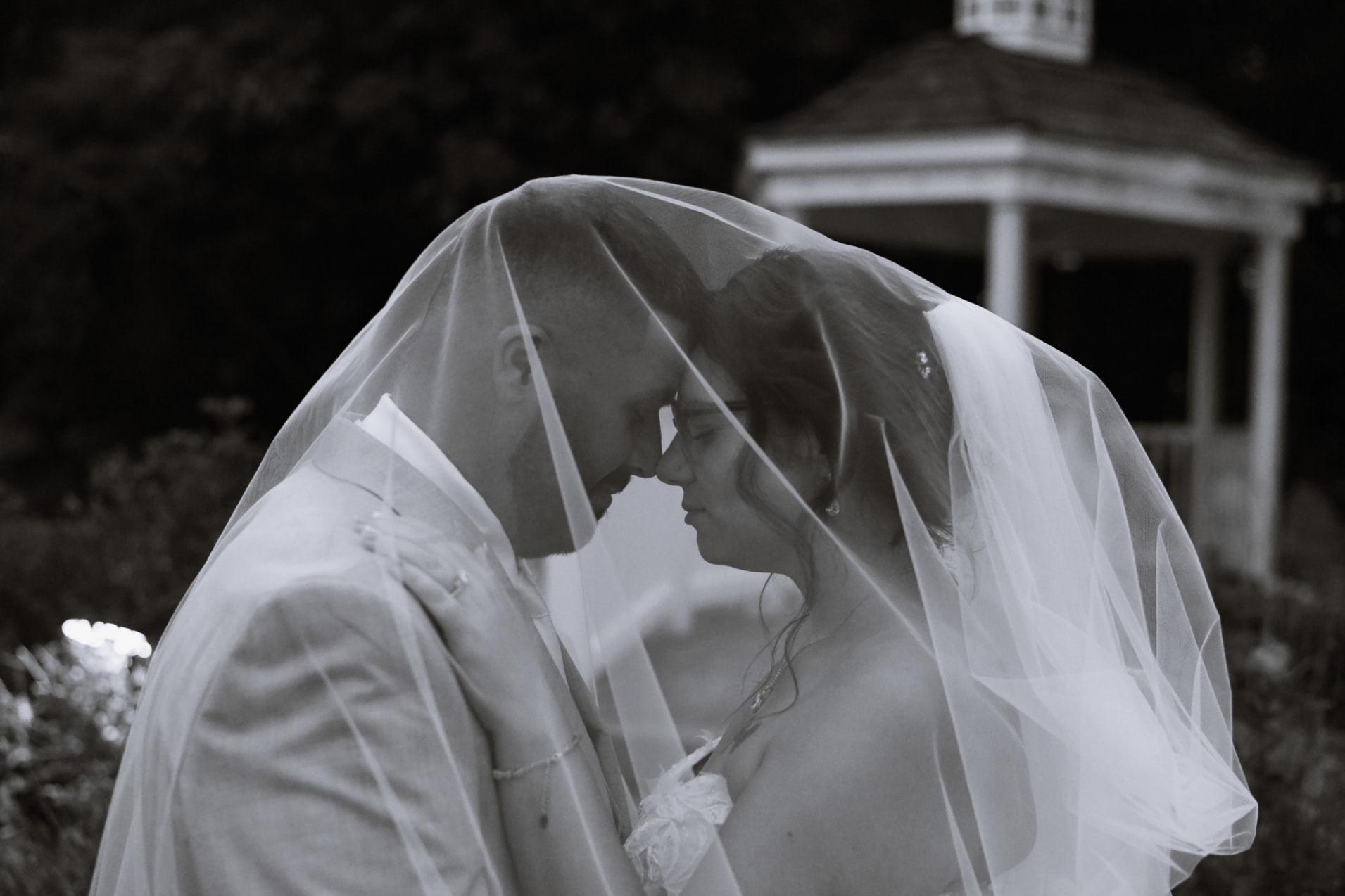 Bride and groom forehead to forehead under veil in black and white
