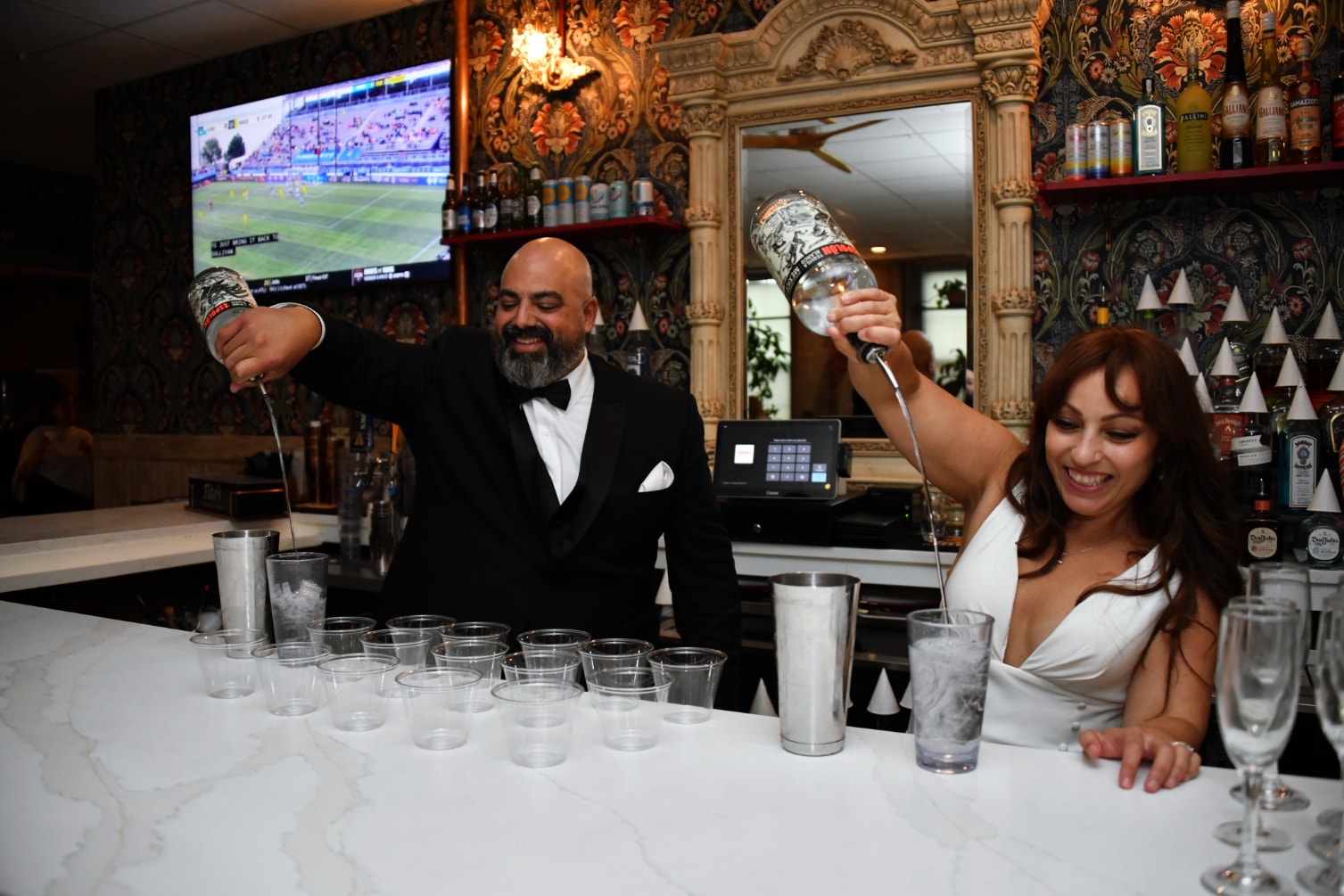 Bride and groom mixing drinks together behind the bar at reception